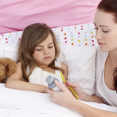 Mother giving her daughter cough medicine