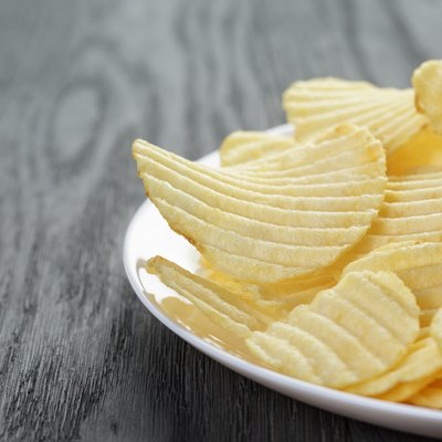 rippled potato chips in white plate on wood table