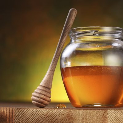 Pot of honey and wooden stick.