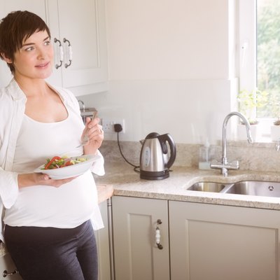 Pregnant woman having bowl of salad