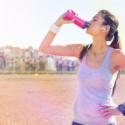 Young sportswoman drinking water after running
