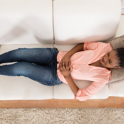 Woman With Stomach Ache Lying On Sofa
