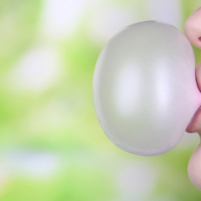 Person doing bubble with chewing gum on bright background