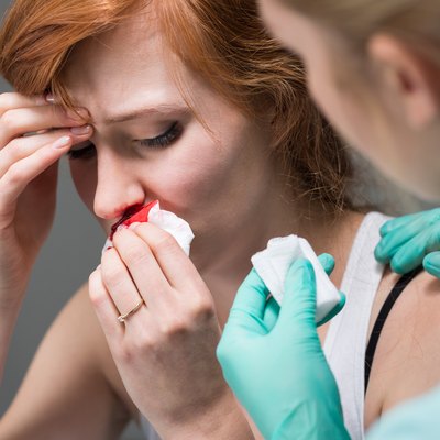 Woman with nosebleed and nurse