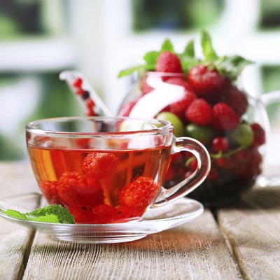 Fruit red tea with wild berries in cup, on table