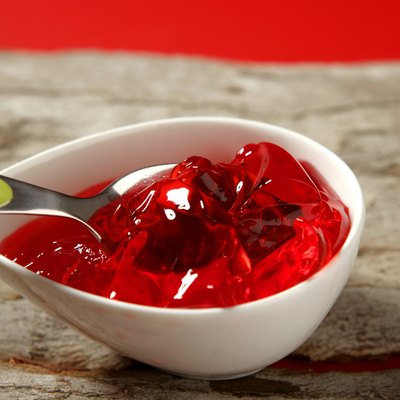 Bowl of strawberry red sweet jelly and green spoon
