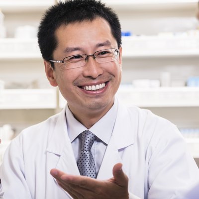 Smiling pharmacist showing prescription medication to a customer