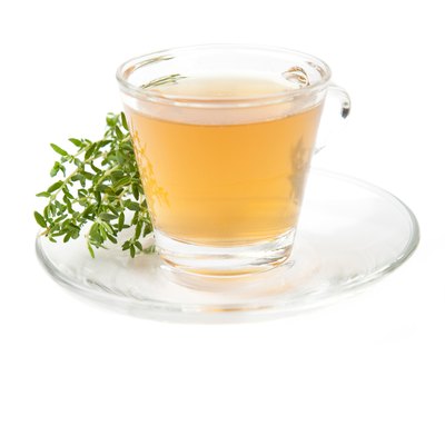 thyme tea with fresh herbs beside teacup,