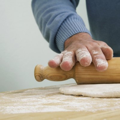 Man preparing dough with rolling pin, close-up