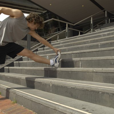 Young man stretching leg on steps, side view