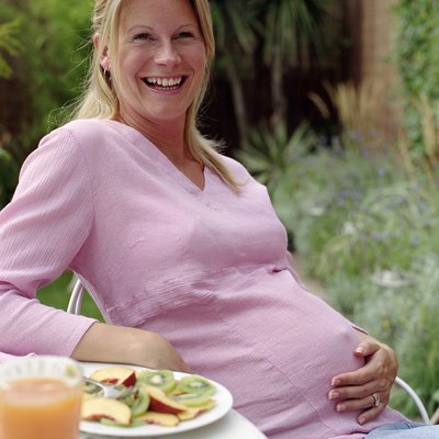 Pregnant woman at breakfast table outdoors, smiling, portrait