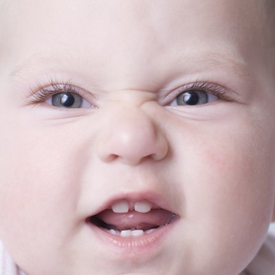 Baby boy pulls funny face with scrunched up nose