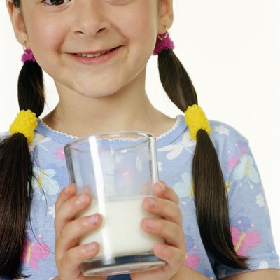 Girl (4-6) holding glass of milk, smiling, portrait