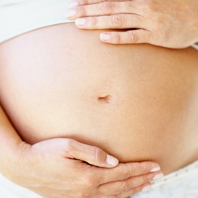 Mid section of a woman holding her pregnant belly