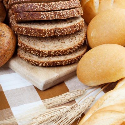 Assortment of baked bread with focus on the sliced loaf.