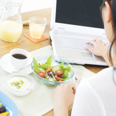 Woman having breakfast while using her laptop