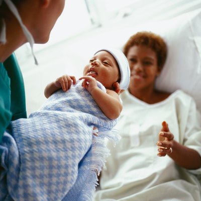 elevated close-up view of a doctor handing a new born baby to the mother