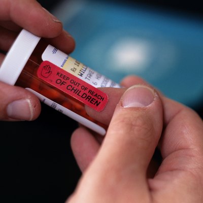 Person holding plastic bottle filled with pills, close-up