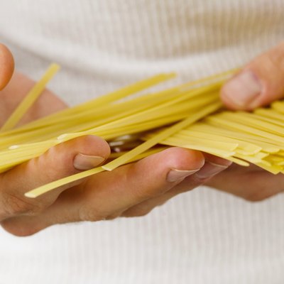 Close-up of uncooked spaghetti in a man's hands