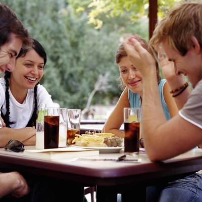 Two couples relaxing at outdoor cafe, smiling