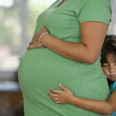 Hispanic girl hugging pregnant mother