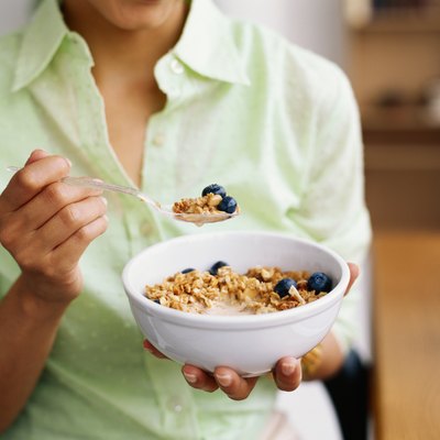 Woman holding bowl of cereal, mid section, close-up