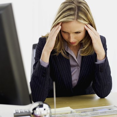 businesswoman sitting at a desk with her hands on her head