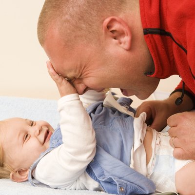 Baby playing with father as diaper is changed