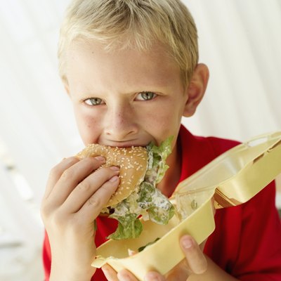 Portrait of a young boy (8-9) eating a hamburger