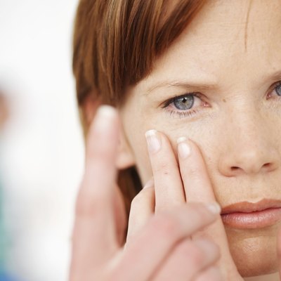Mid adult woman putting in contact lens, close-up