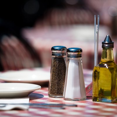 Salt and pepper shakers and olive oil on restaurant table