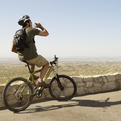 Hispanic man drinking water on bicycle