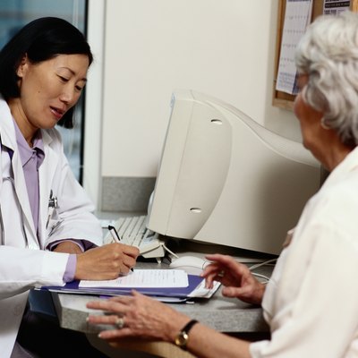 Doctor writing prescription for mature female patient