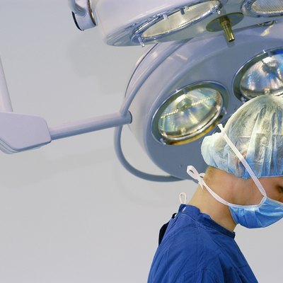 Head and shoulders image of doctor in surgical scrubs under operating room light, close-up, part of