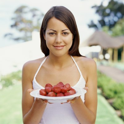 Portrait of a young woman holding a plate of strawberries