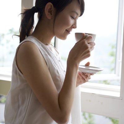 Woman drinking tea by window in home