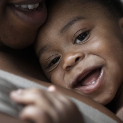 baby being cuddled by mum smiling