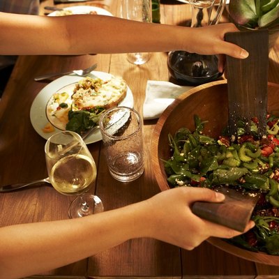 Young woman mixing salad at dinner party