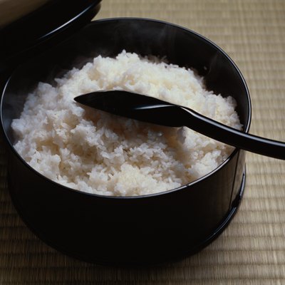 Cooked rice in bowl with scoop, high angle view