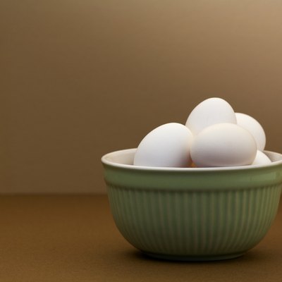 White eggs in green bowl on brown table