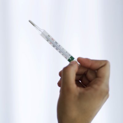 a hand holding a medical thermometer