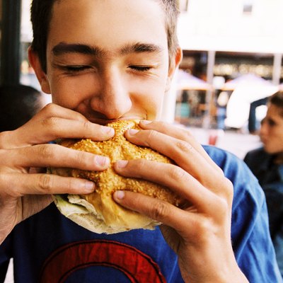 close-up of a young man eating a sandwich in a caf+?