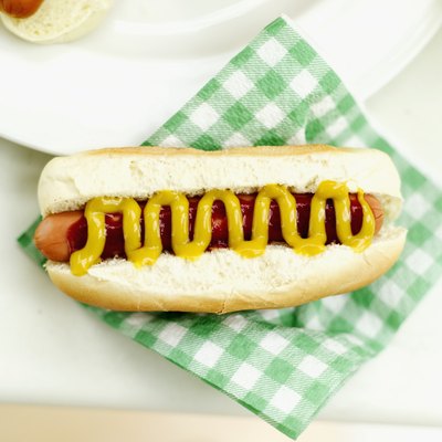 Close-up of a hotdog with mustard on a napkin