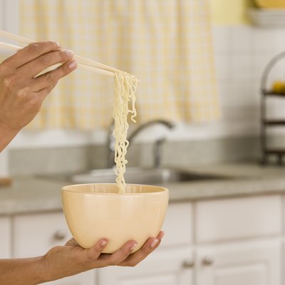 Woman holding chopsticks with ramen and bowl