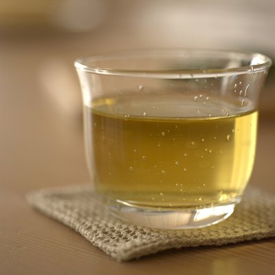 Glass of green tea on coaster, close-up