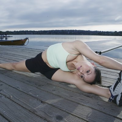 Young woman exercising on dock at lake