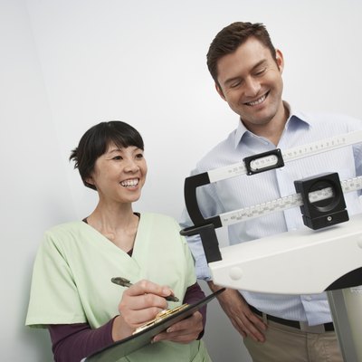 Man standing on weighing scales beside nurse in hospital