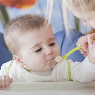 Portrait of young woman feeding her baby