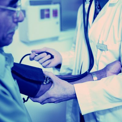 Doctor checking blood pressure of elderly male patient (blue tone)