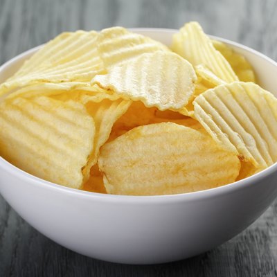 rippled organic chips in white bowl on wooden table